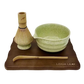 Discover the beauty of the 5 Piece Matcha Whisk Set with Wooden Display Board from Leigh Leaf, showcasing a green matcha bowl, bamboo whisk, and a wooden base for a refined tea experience.