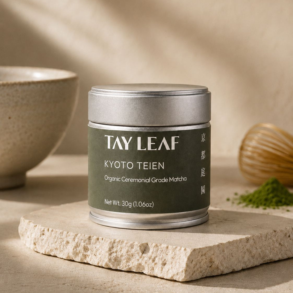 Tay Leaf Kyoto Teien matcha container on a stone surface with a bowl and leaves in the background.